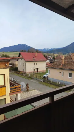 Výhled z balkonu přes střechy na zasněžené hory