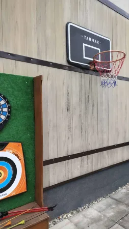 Basketbalový koš a terče pro šipky na dřevěné stěně v zahradě
