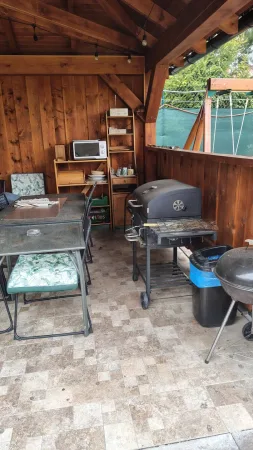 Krytá venkovní kuchyně s grilem a posezením pod pergolou