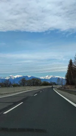 Výhled na zasněžené vrcholky Vysokých Tater z dálnice s projíždějícím motorkářem