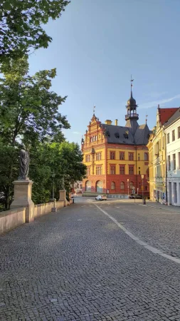 Dlážděná ulice v Chrudimi vedoucí ke žlutočervené budově Regionálního muzea s věžičkou