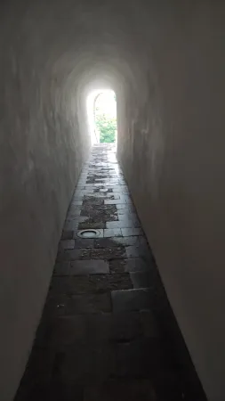 Dlážděný tunel Myší díra v Chrudimi vedoucí ke světlému východu mezi zelení