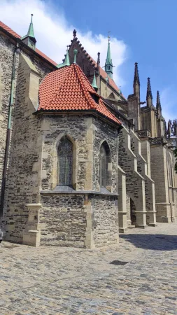 Gotická apsida chrámu svatého Bartoloměje s červenou střechou a dlážděným náměstím