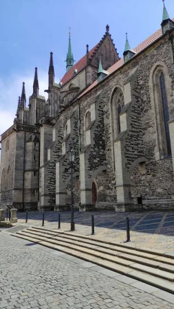 Boční strana gotického chrámu svatého Bartoloměje s opěrnými pilíři a dlážděným náměstím