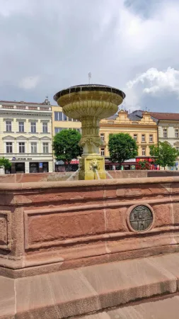 Kamenná kašna s lvími hlavami na náměstí v Kolíně a okolní historické domy