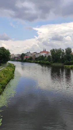 Pohled z lávky na řeku Labe a historické centrum Kolína s věžemi kostela v dálce