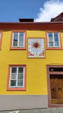 Žlutý dům v Kolíně se slunečními hodinami s nápisem Fac dum lucet sol a dřevěnými dveřmi