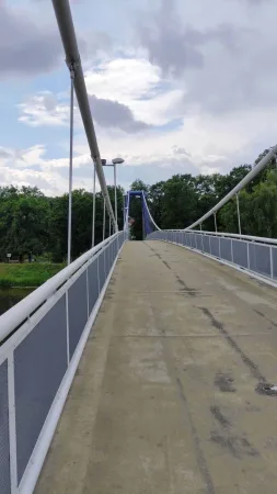 Bílá visutá lávka s ocelovým zábradlím a lany nad řekou Labe v Kolíně