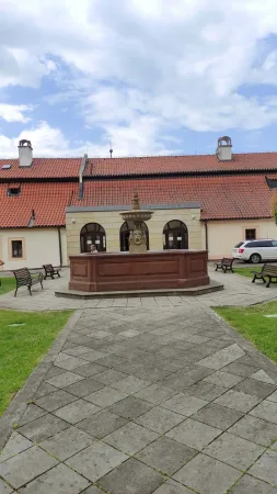 Červená kamenná kašna s lavičkami na nádvoří zámku v Poděbradech