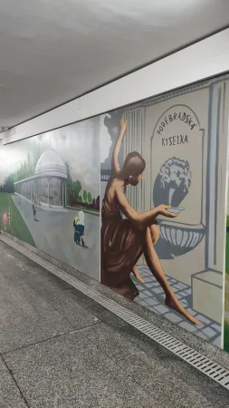 Malba ženy s pítkem a nápisem Poděbradská kyselka v podchodu