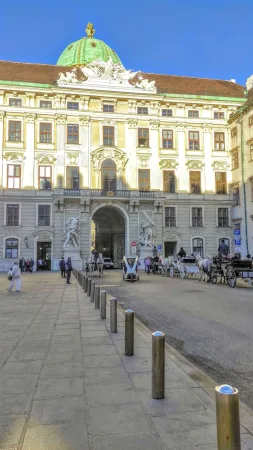 Nádvoří s koňskými kočáry (fiakry) a kupolí Hofburgu