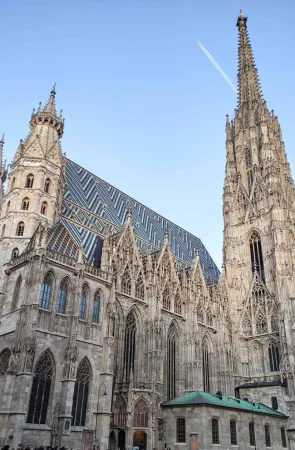 Barevná taškovaná střecha a štíhlá věž katedrály Stephansdom při soumraku