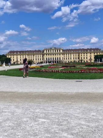 Žena procházející se před zámkem Schönbrunn s květinovými záhony