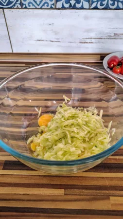 Nastrouhaná cuketa s vajíčkem a sýrem ve skleněné míse, příprava těsta na pizzu