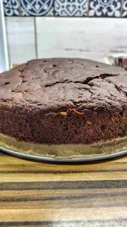 Detail upečeného koláče s čokoládou na kulatém plechu.