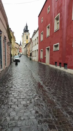 Vlhká dlážděná ulička v centru Székesfehérváru s výhledem na kostelní věž