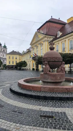 Kašna s reliéfy lvů na hlavním náměstí obklopeném žlutým palácem