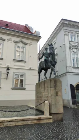 Jezdecká socha bojovníka na koni na kamenném podstavci uprostřed historického náměstí