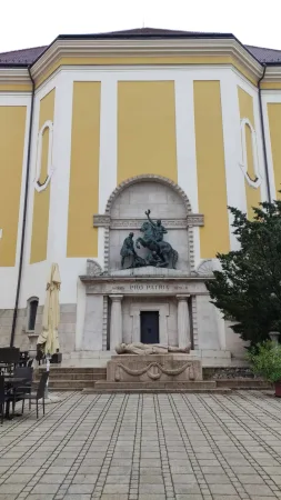 Pomník Pro Patria se sochou jezdce na koni před žlutou fasádou budovy