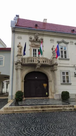 Barokní vstupní portál biskupského paláce zdobený sochami světců a maďarskými vlajkami