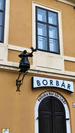 Cedule baru Borbár se zdobenou soškou nad vchodem do podniku
