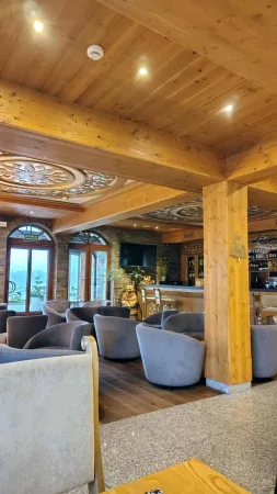 Hotelový bar s křesly a dřevěnými trámy ve stylu horské chalupy