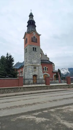 Cihlový kostel s kamennou věží a křížem v Bialce Tatrzanskiej
