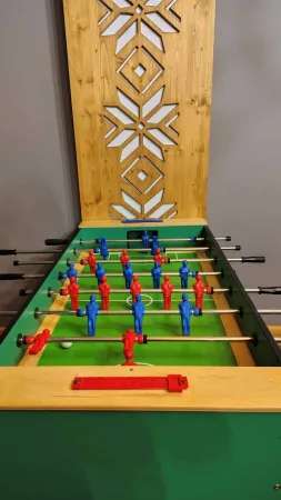 Stolní fotbálek s modrými a červenými figurkami v herně hotelu