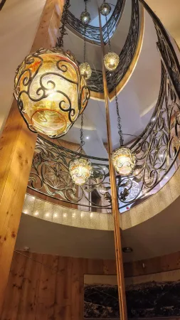 Točité schodiště s kovaným zábradlím a barevnými lampami v hotelu Gorski
