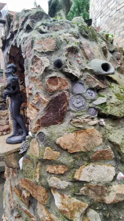Detail kamenné zdi s vsazenými mincemi a mušlemi