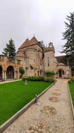 Hrad s kopulovou věží a štěrkovou cestou kolem zeleného trávníku
