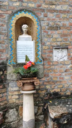 Mozaikový výklenek s bustou ženy, básní a čerstvými květinami