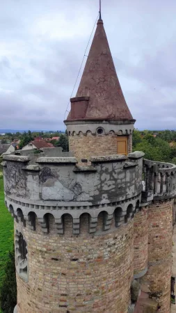Detail hradní věže s kuželovou červenou střechou a cimbuřím