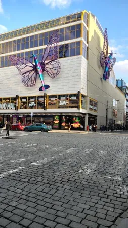 Velká kovová socha vážky na fasádě obchodního domu Máj