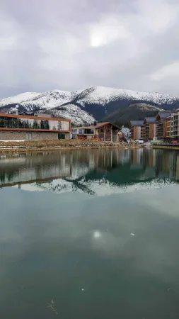 Jezero s odrazem horského střediska a zasněžených vrcholků hor