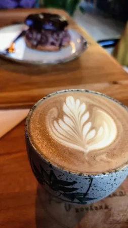 Hrnek s cappuccinem na dřevěném podnosu v kavárně Kafe a Květina