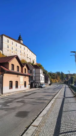 Die Burg von Ledeč auf dem Felsen über der Straße und alten Häusern unter blauem Himmel mit herbstlichen Bäumen