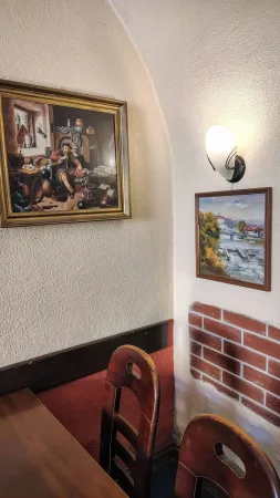 Bilder an der Wand eines gewölbten Restaurants mit Ziegelputz-Imitation und Holzstühlen