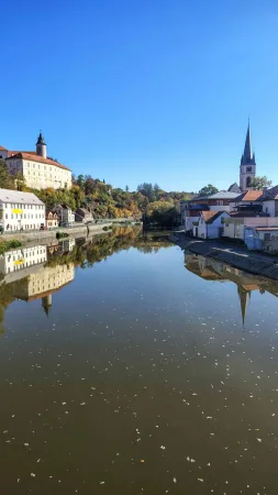 Der Fluss Sázava in Ledeč nad Sázavou mit Spiegelung der Burg, der Häuser und des Kirchturms im Wasser
