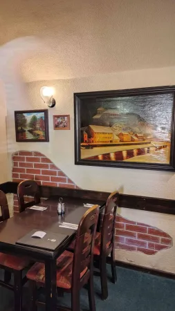 Restaurantinnenraum mit Holzstühlen und einem großen Bild der Stadt über dem Fluss an der Wand