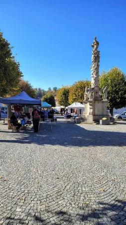 Marktstände und die barocke Pestsäule auf dem sonnigen gepflasterten Platz in Ledeč nad Sázavou
