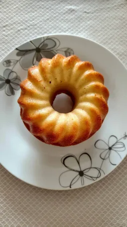 Malá upečená bábovka z horkovzdušné fritézy na bílém talíři s květinovým vzorem, pohled shora