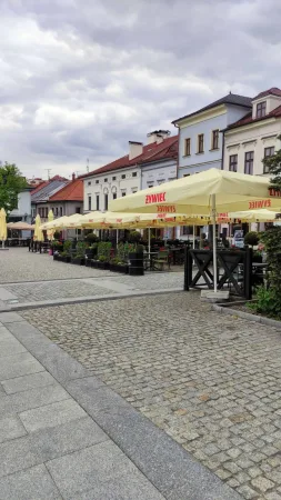 Hlavní náměstí Bielska-Białe s barevnými secesními domy a žlutými slunečníky kaváren.