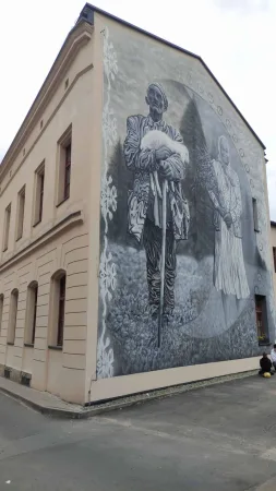 Velká nástěnná malba s postavami muže a ženy na štítu domu.