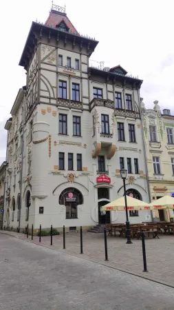 Secesní dům s věžičkou a kavárnou v přízemí na náměstí.