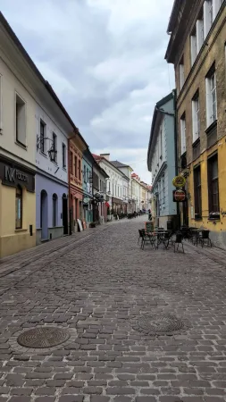 Klidná dlážděná ulička se starými domy a kavárenskými zahrádkami v centru města.
