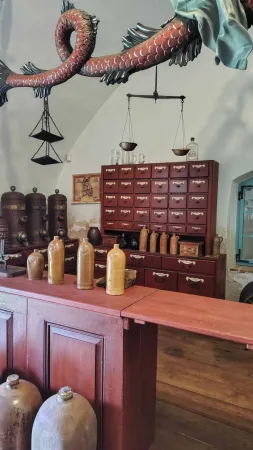 Expozice kupeckého krámu se skleněnými lahvičkami a starými váhami