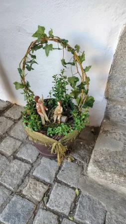 Květináč s břečťanem a drobnými figurkami na hradním nádvoří