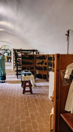 Klenutá místnost s regály plnými starých tiskařských forem