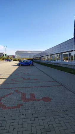 Modré auto zaparkované na prázdném parkovišti před moderní halou